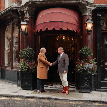 two men in suits shake hands outside of pub in London